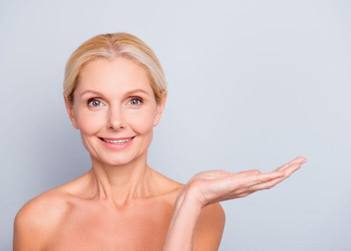 Advertisement concept. Portrait with empty place of charming, attractive, nude woman with smooth, soft, perfect, ideal, pure, fresh skin holding copy space on her palm, isolated on grey background